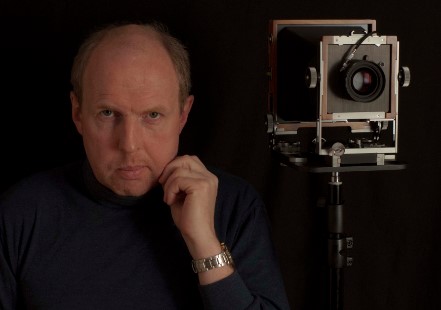 Didier Descartes posant avec sa chambre photographique grand format à soufflet.